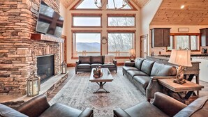 A spacious living room with a stone fireplace, leather sofas, and large windows offering mountain views. - Mountainside Family Retreat w/ Deck in Banner Elk! (Banner Elk)