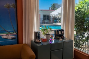Habitación con vista a una piscina, una planta en maceta y un escritorio con un tostador y libros.