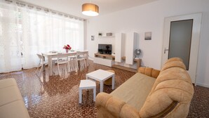 Un salon moderne comprenant un canapé, une table à manger avec des chaises, un téléviseur et une cheminée.