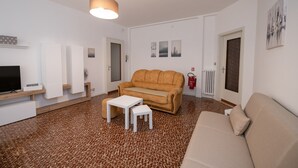Un salon moderne avec un canapé beige, une table basse blanche et un téléviseur posé sur un meuble en bois.