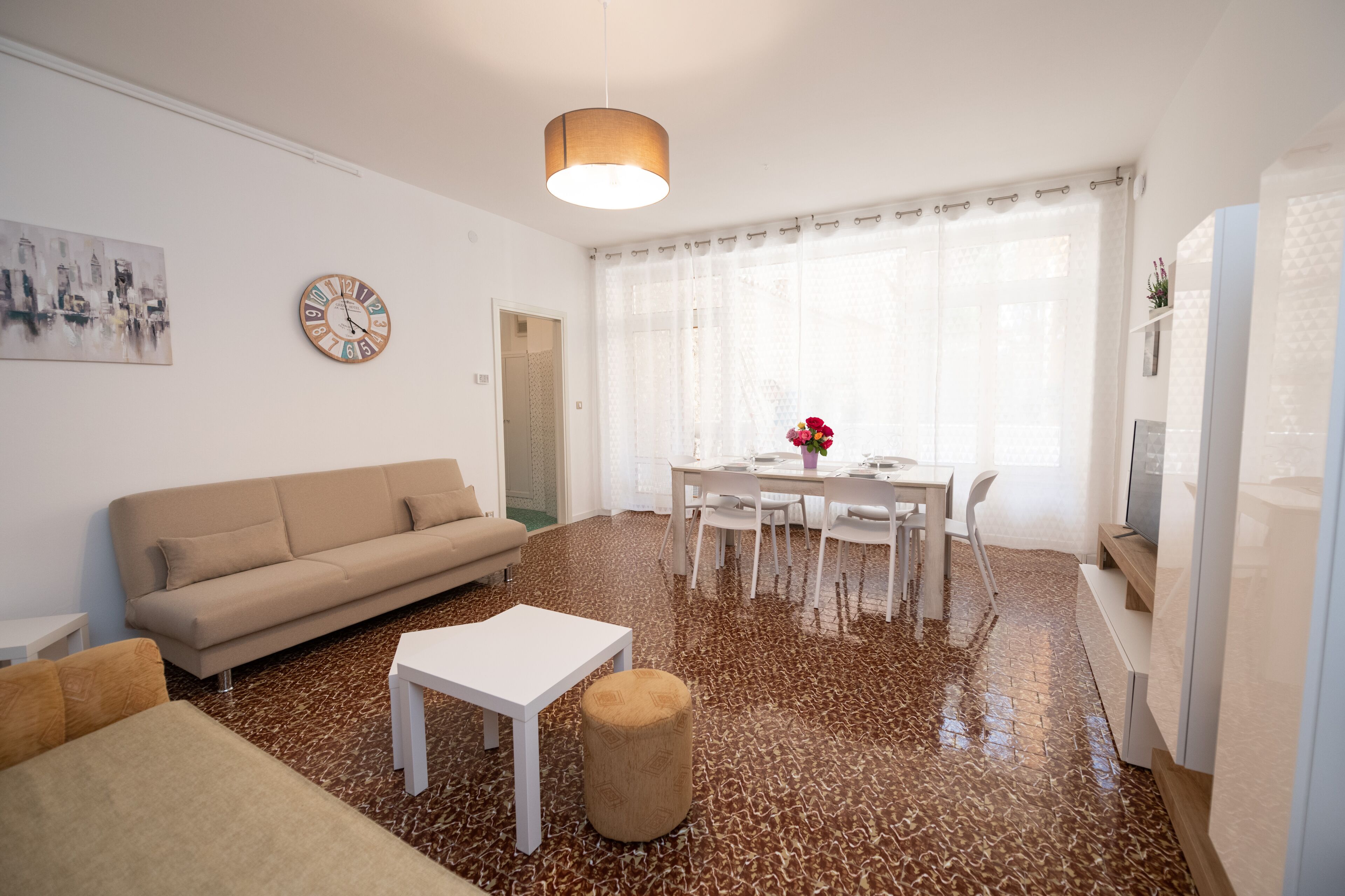 A modern living room with a sofa, coffee table, and dining table with chairs.