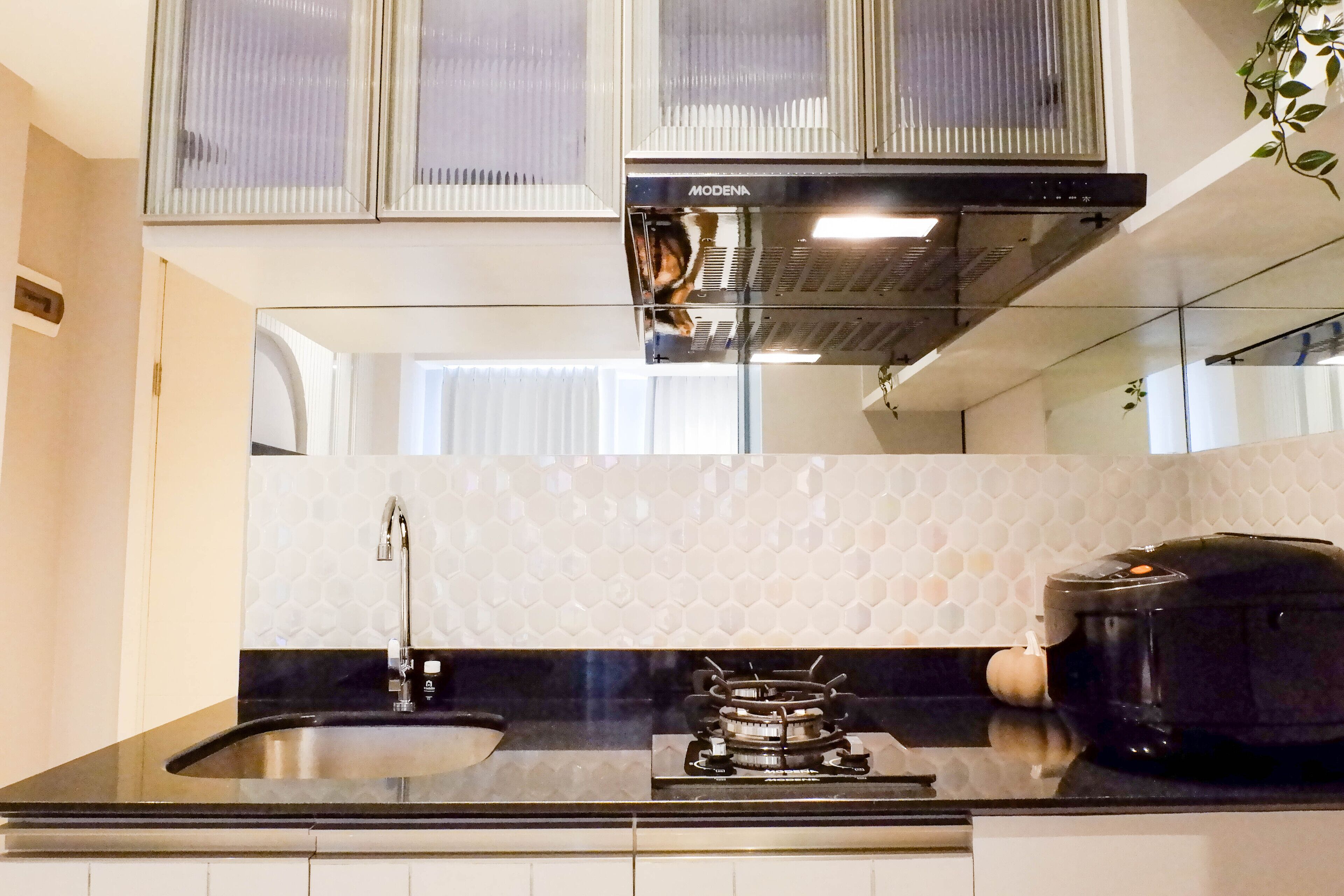 Una cocina moderna con encimera negra, pileta de acero inoxidable, cocina a gas y cafetera negra.