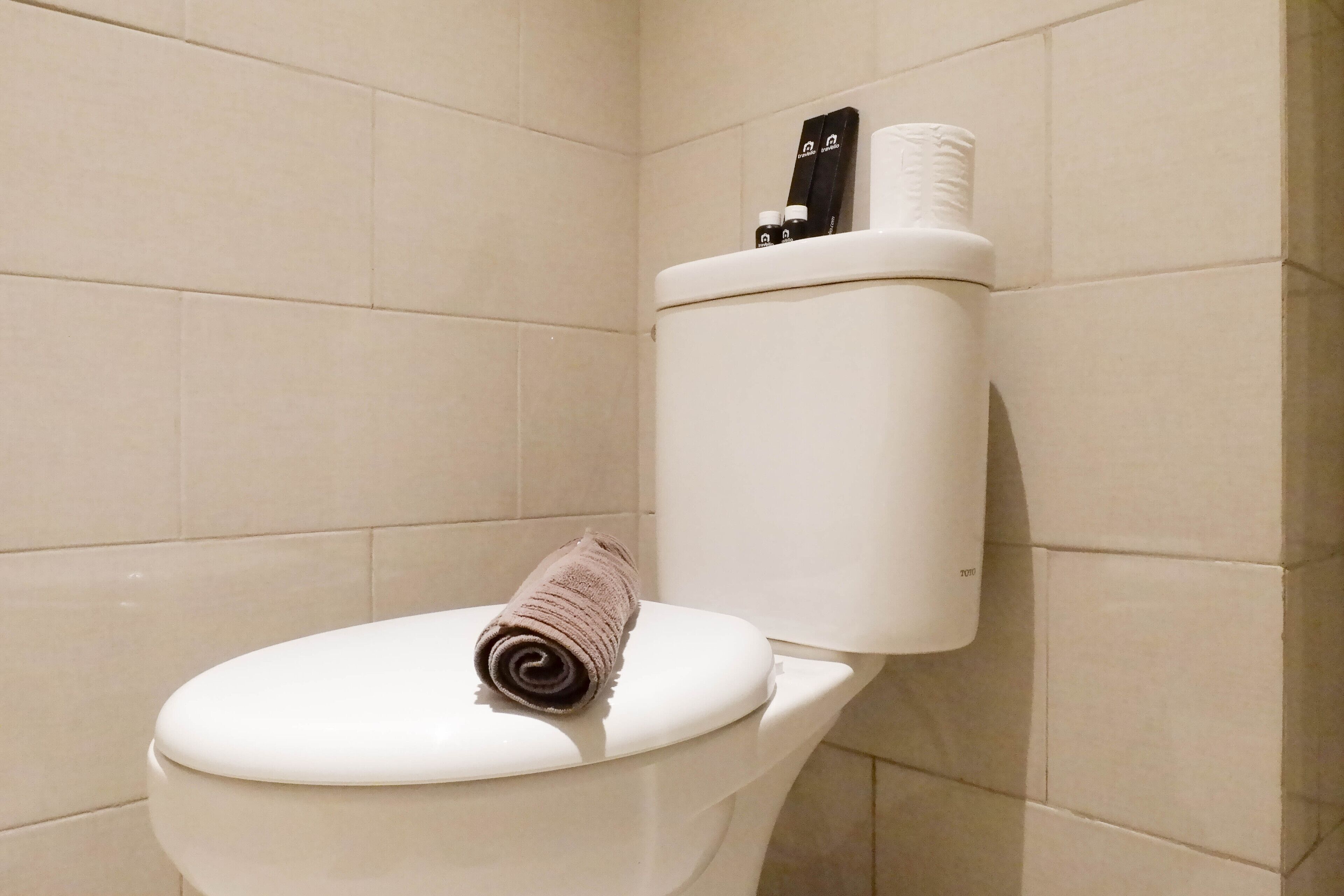 A toilet with a towel on the seat and toilet paper on the holder.