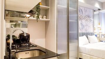 Habitación de hotel moderna con cocina que incluye estufa, pileta y plantas colgantes.