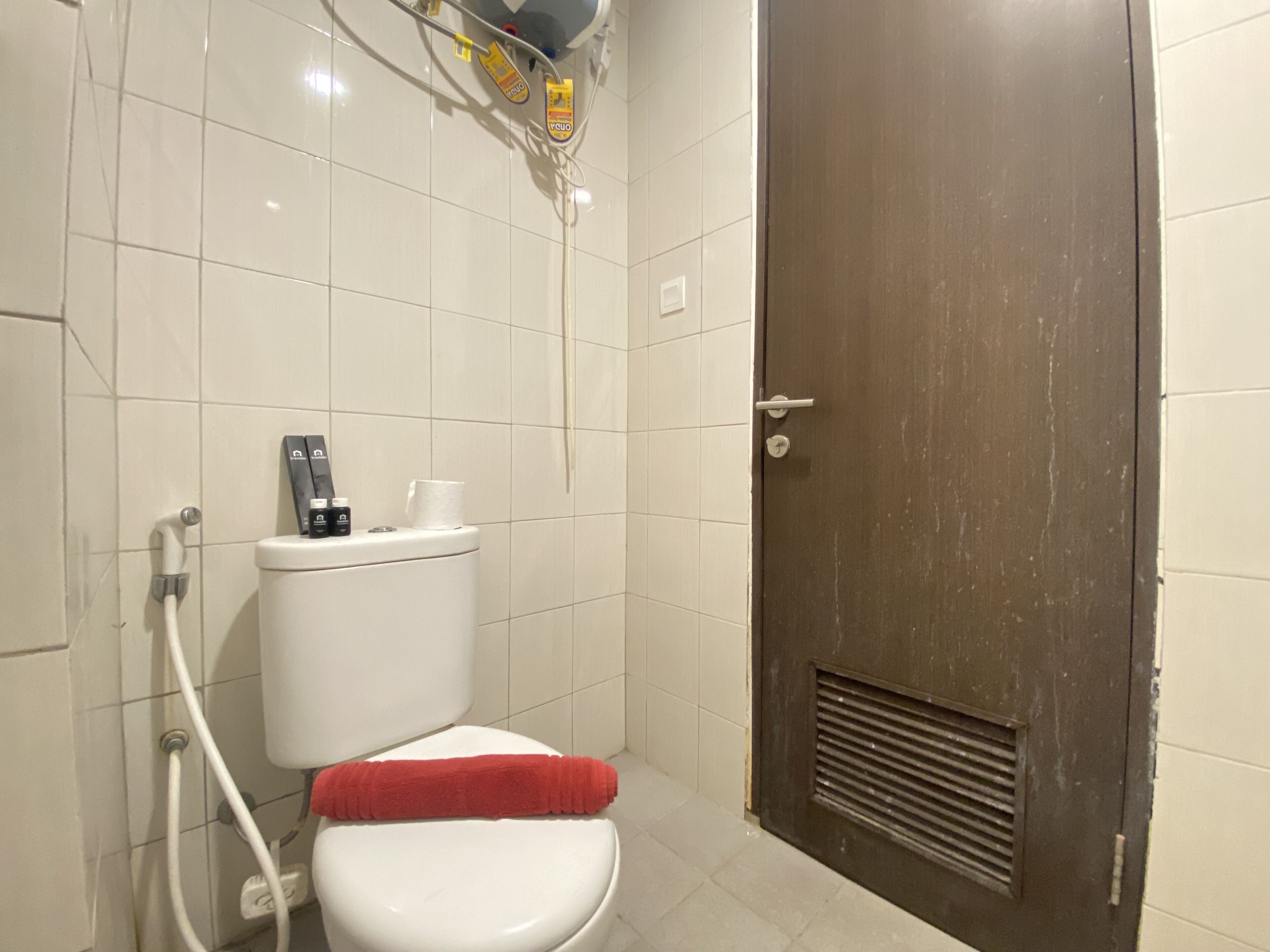 Un baño con inodoro, una toalla roja y un panel de control de la ducha.