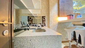A modern bathroom with a granite countertop, a large mirror, and a built-in sink. - Modern 2Br Apartment At Suites @Metro (Bandung)