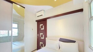 A bedroom with a bed, a sliding glass door, a wall-mounted air conditioner, and a window. - Modern 2Br Apartment At Suites @Metro (Bandung)