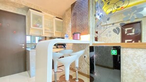A modern kitchen with a built-in island, bar stools, and a refrigerator. - Modern 2Br Apartment At Suites @Metro (Bandung)
