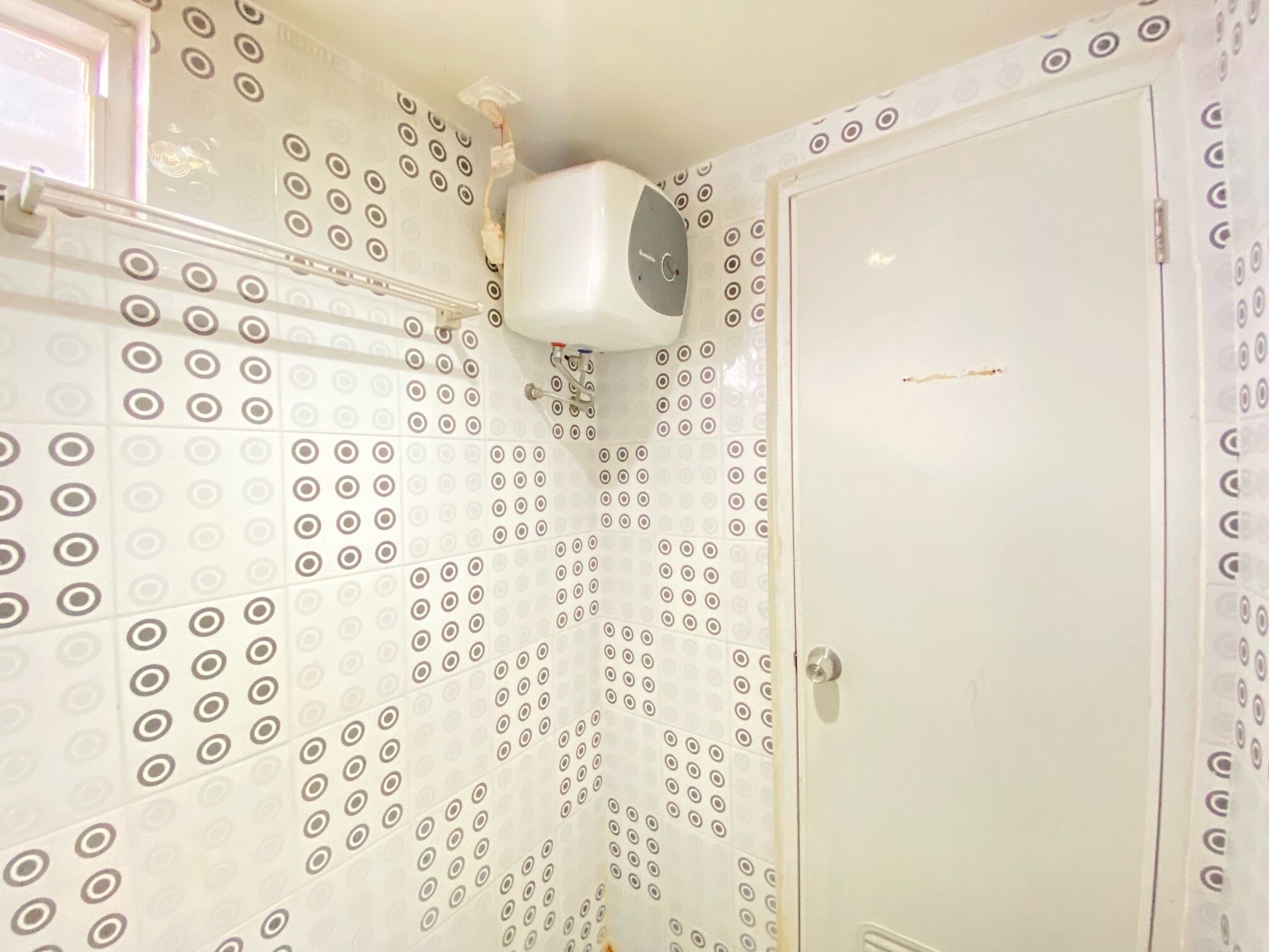 A bathroom with patterned tiles, a white sink, and a door with a handle.