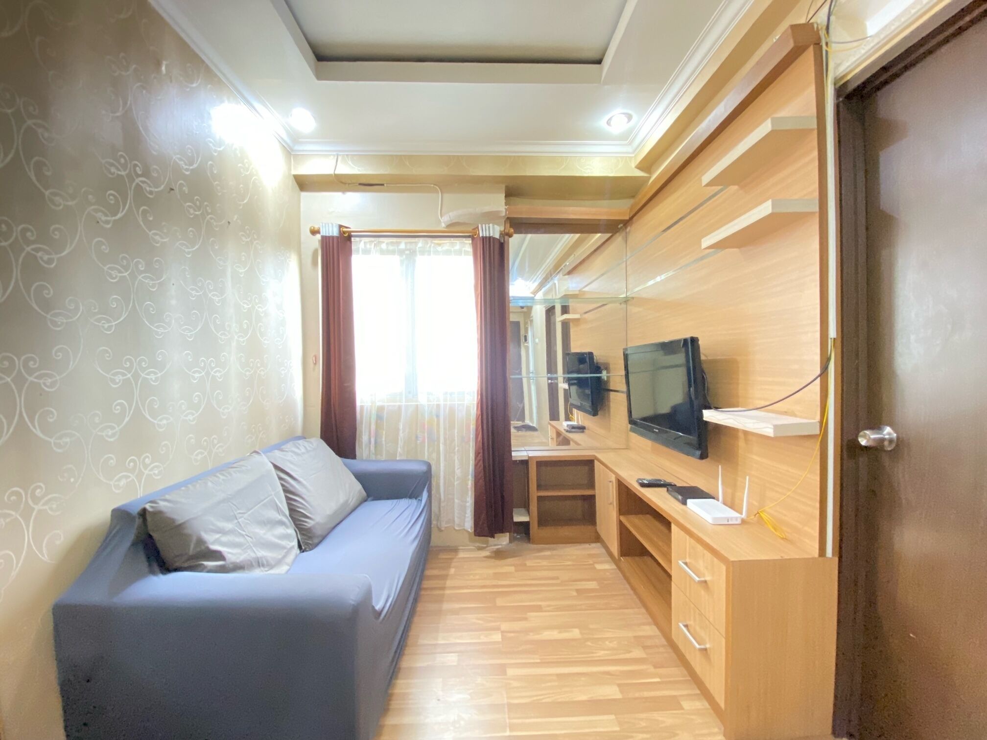 A compact living space with a sofa, a TV, and a wooden cabinet.