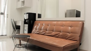 A modern living room with a brown leather sofa, a round black wire table, and a coffee machine. - Cozy Stay 2Br Springlake Summarecon Bekasi Apartment (Bekasi)