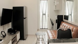 A compact living space with a flat-screen TV, a refrigerator, a leather sofa, and a glass coffee table. - Cozy Stay 2Br Springlake Summarecon Bekasi Apartment (Bekasi)