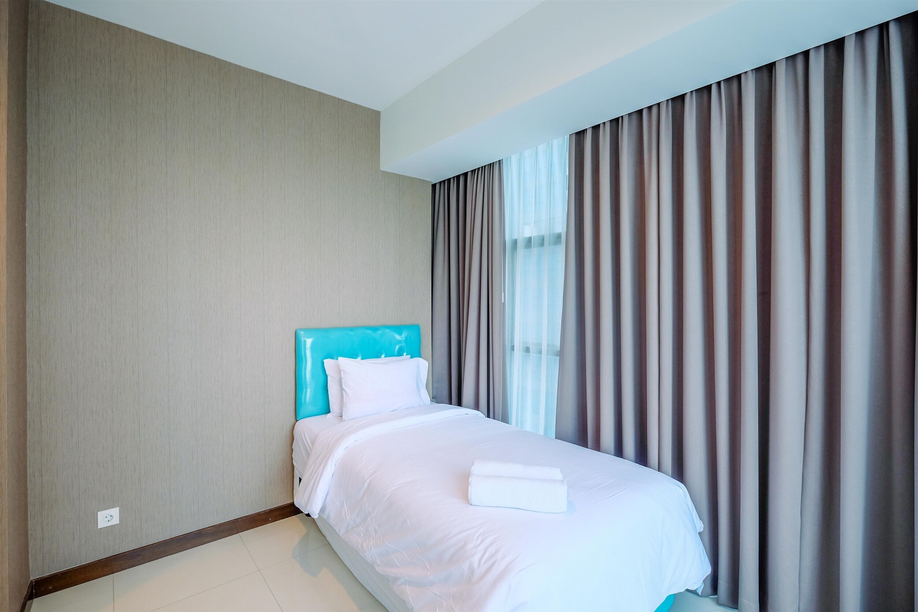 Une chambre d’hôtel avec un lit, une tête de lit et des rideaux.