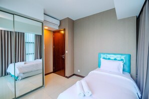 A hotel room with a bed, a mirror, a door, and an air conditioning unit.