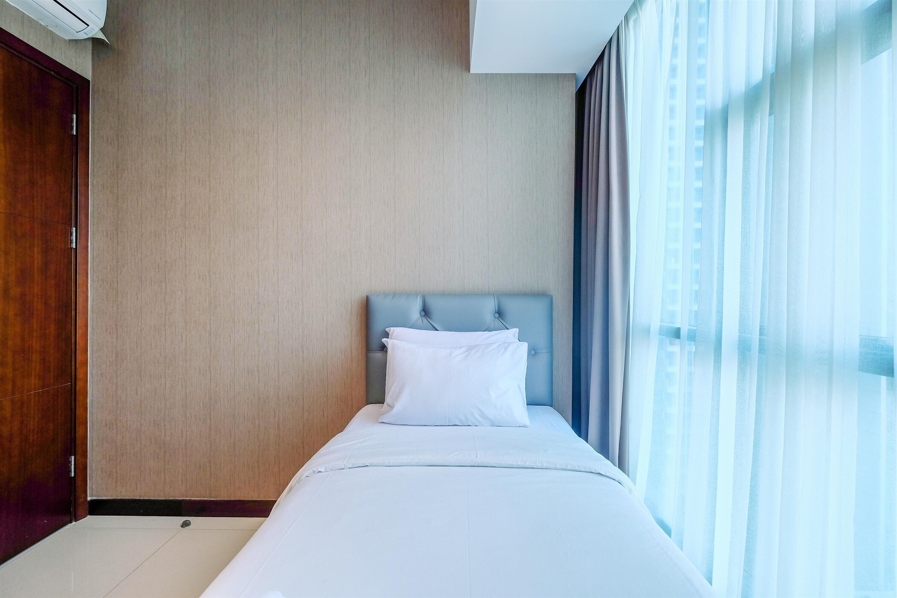 Une chambre d’hôtel avec un lit, une armoire en bois et une fenêtre avec des rideaux.