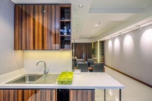 A modern kitchen with a white countertop, stainless steel sink, and wooden cabinets.