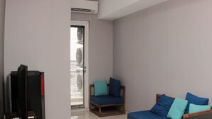 A modern living room with a TV, a wooden chair, and a sofa with blue cushions.