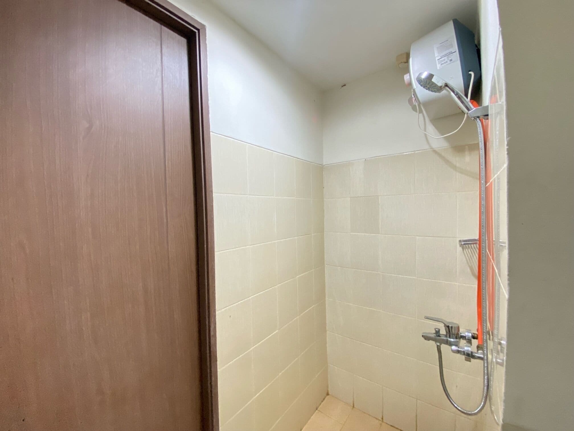 A small, tiled bathroom with a shower and a door.
