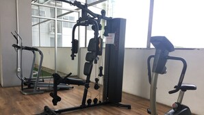 A gym with various exercise equipment, including a multi-gym machine and an elliptical.