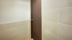 A bathroom with a door, tiled walls, and a vent on the ceiling.