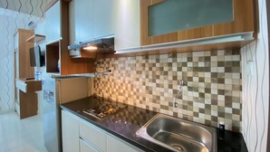A modern kitchen with a black countertop, stainless steel sink, and checkered backsplash.