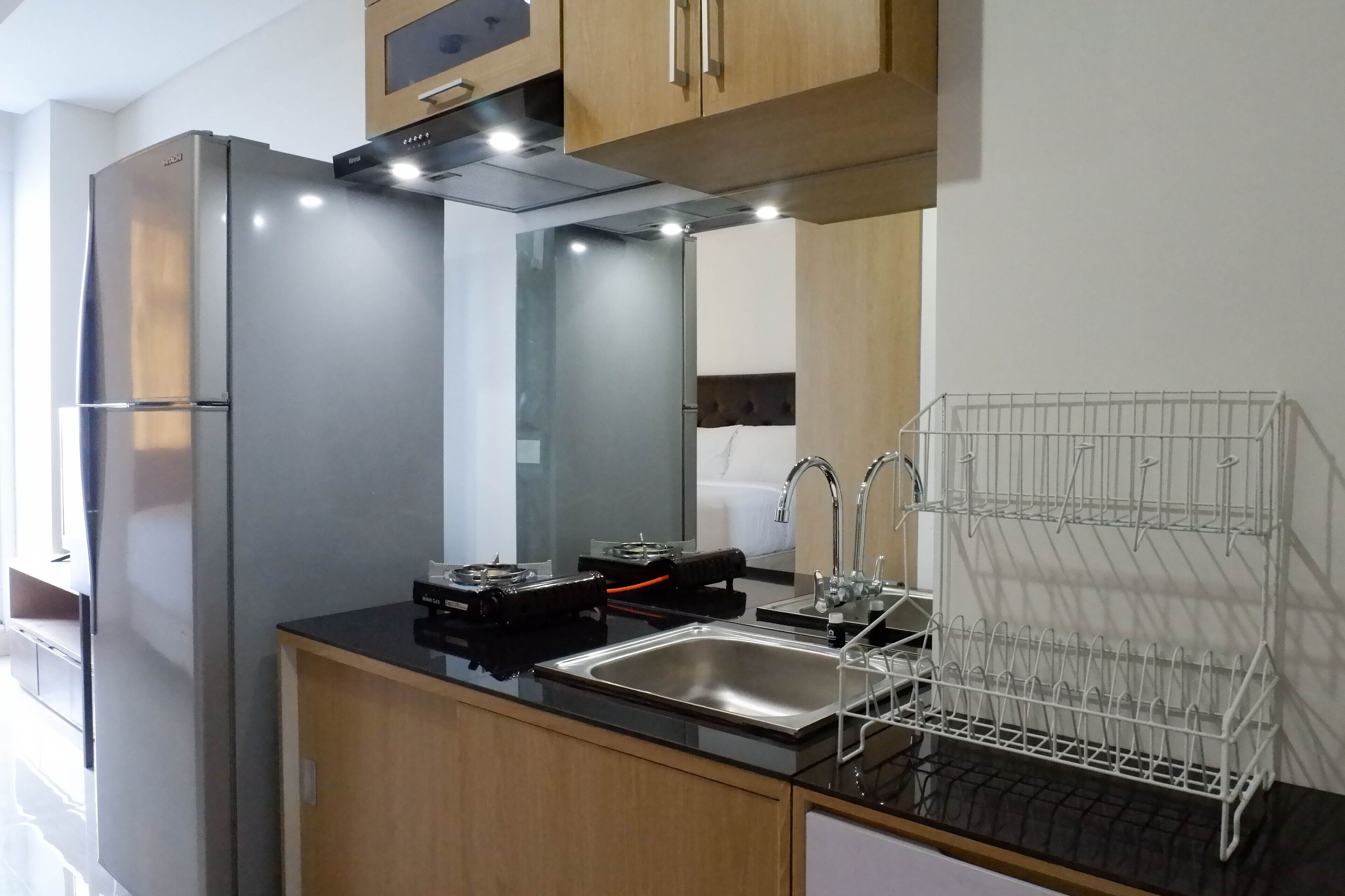 Una cocina moderna con un refrigerador de acero inoxidable, una encimera negra, un fregadero y un escurreplatos.