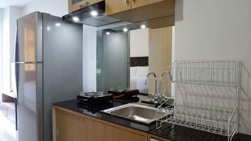 Una cocina moderna con un refrigerador de acero inoxidable, una encimera negra, un fregadero y un escurreplatos.