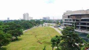 A park with a river, surrounded by buildings and trees.