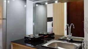 A modern kitchen with a refrigerator, a stove, a sink, and a mirror.