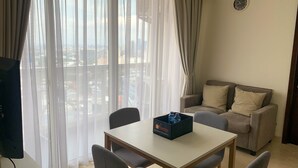 A hotel room with a balcony, a sofa, a dining table, and a box of travel essentials.