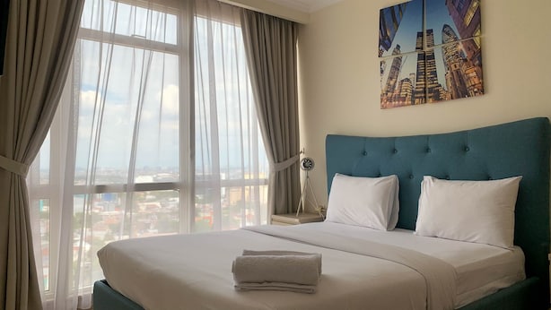 A hotel room with a large bed, a cityscape view, and a painting on the wall.