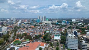 A cityscape with a mix of high-rise buildings and smaller residential structures, a river running through the city, and a clear sky. - Elegant 2Br With Private Lift At Menteng Park Apartment (Jakarta)