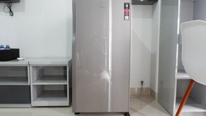 Una cocina moderna con un refrigerador de acero inoxidable, una silla blanca y una pequeña mesa con botellas de agua.