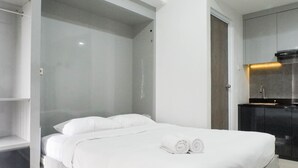 Una habitación de hotel moderna con cama, armario empotrado y una pequeña kitchenette.