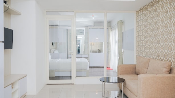 A modern living room with a sofa, a coffee table, and a glass door leading to a bedroom.