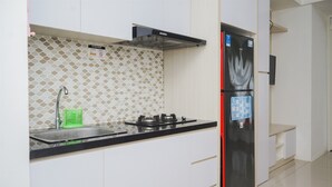 A kitchen with white cabinets, a black refrigerator, a gas stove, and a tiled backsplash.
