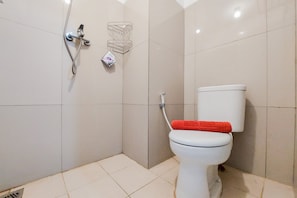 Een badkamer met een toilet, douche en betegelde vloer.