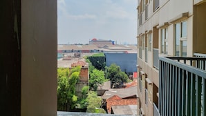 A view from a balcony overlooking a cityscape with buildings and a large structure in the distance.