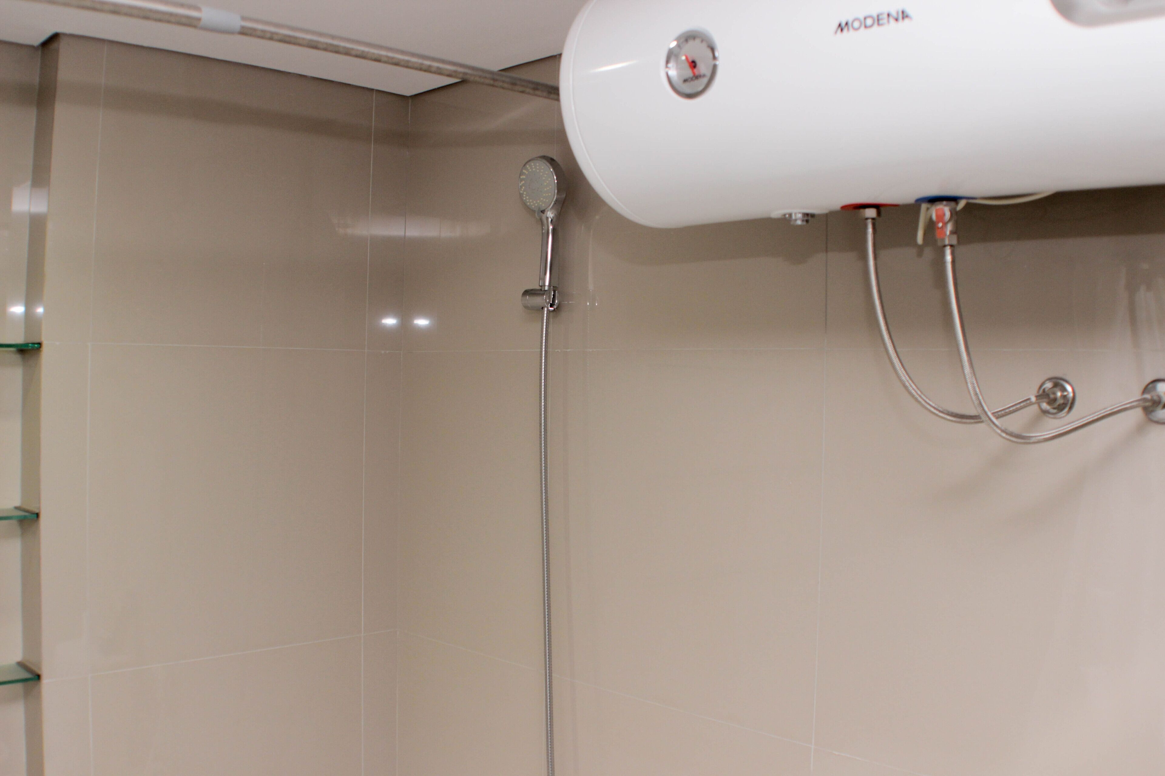 A shower with a handheld showerhead and a wall-mounted control panel.