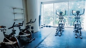 A gym with stationary bikes and dumbbells, large windows, and a white wall. - Best Deal Studio Apartment At High Point Serviced (Surabaya)