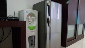A compact kitchen with a stainless steel refrigerator, a water dispenser, and a microwave. - Best Deal Studio Apartment At High Point Serviced (Surabaya)