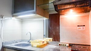 A kitchen with a sink, a stove, and a trash bin. - Best Deal Studio Apartment At High Point Serviced (Surabaya)