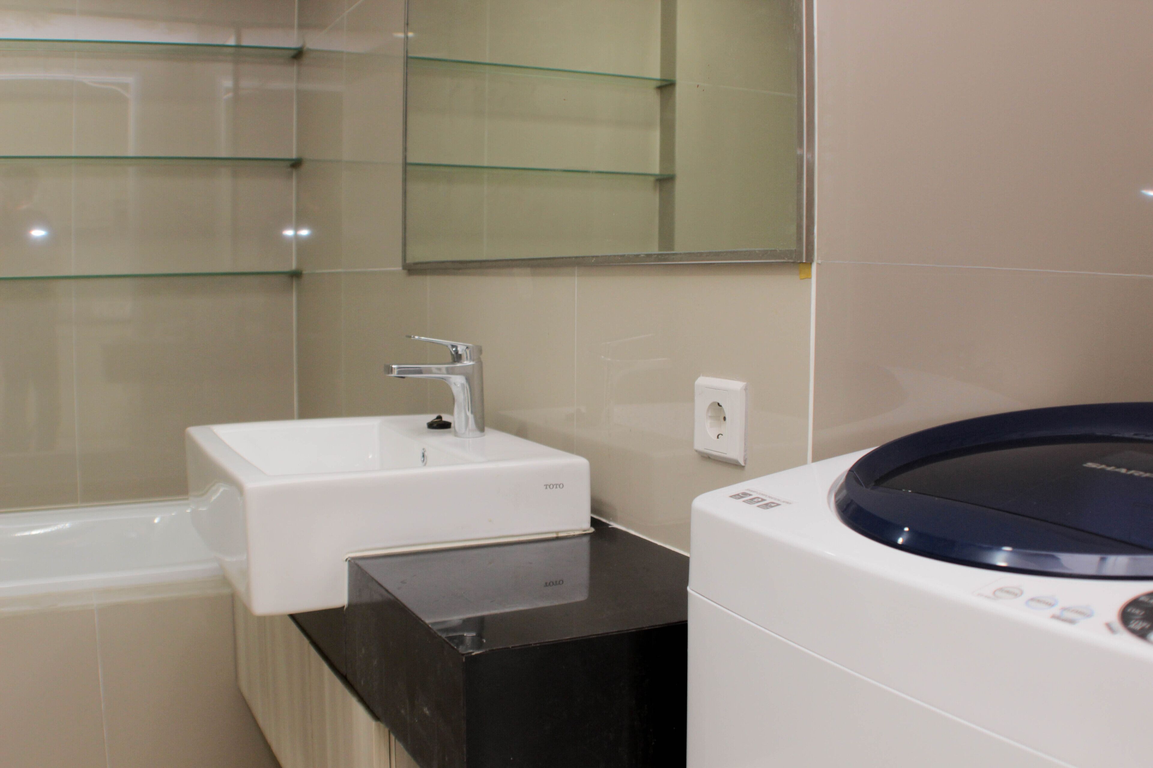 A modern bathroom with a white sink, a black countertop, and a built-in washing machine.