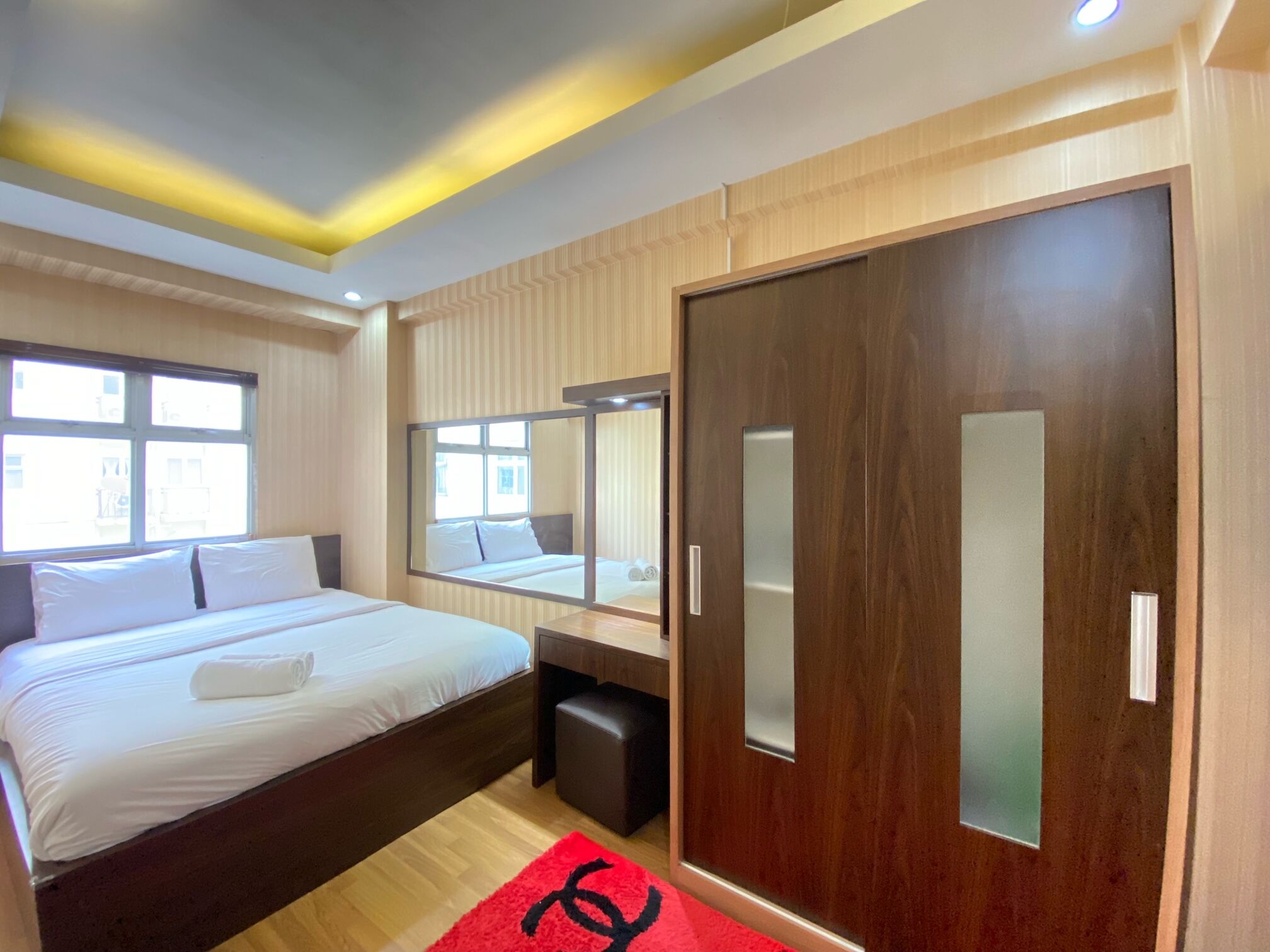 Une chambre d’hôtel avec un grand lit, une armoire, un miroir et une fenêtre.