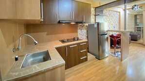 A modern kitchen with wooden cabinets, a stainless steel refrigerator, and a marble countertop. - Spacious And Private 1Br Apartment Suites @Metro (Bandung)