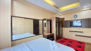 A hotel room with a bed, a large mirror, a TV mounted on the wall, and a red patterned rug. - Spacious And Private 1Br Apartment Suites @Metro (Bandung)