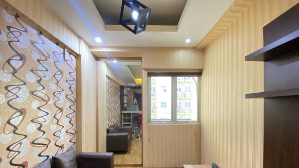 A modern interior with a wooden floor, a sofa, a table, and a patterned wall. - Spacious And Private 1Br Apartment Suites @Metro (Bandung)