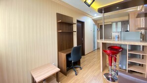 A modern kitchen with wooden cabinets, a red bar stool, and a small wooden table. - Spacious And Private 1Br Apartment Suites @Metro (Bandung)