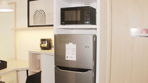 A compact kitchen with a stainless steel refrigerator, a microwave, and a framed picture on the wall. - Serene And Cozy 2Br At Meikarta Apartment (Cikarang)