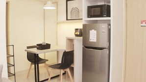 A compact kitchen with a refrigerator, microwave, and a coffee maker on the countertop. - Serene And Cozy 2Br At Meikarta Apartment (Cikarang)